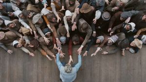 A crowd of people reach out their hands to an actor on stage.