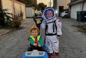 Owen in a blue car, dressed as a construction worker and Ryan dressed as an astronaut.