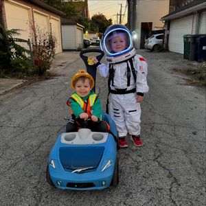 Owen in a blue car, dressed as a construction worker and Ryan dressed as an astronaut.